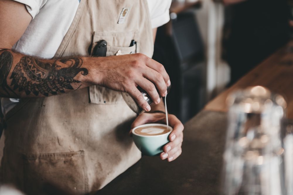 Steamed milk being poured into cup of coffee.