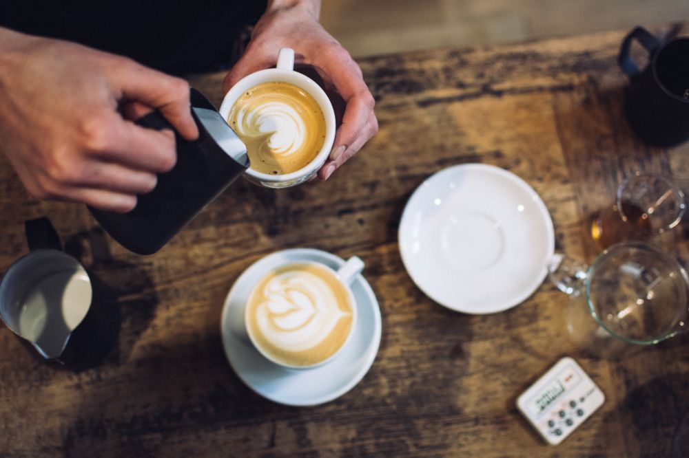 Steamed milk making a design as it is poured into cup of coffee.